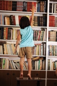 1163288_stock-photo-kid-trying-to-reach-a-book-in-the-library